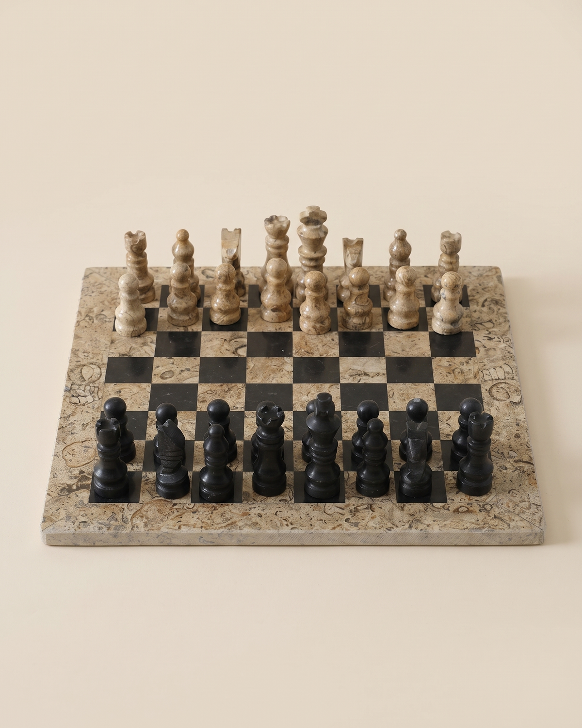 Chess Set IV - fossil stone and black marble chess set on ivory studio background