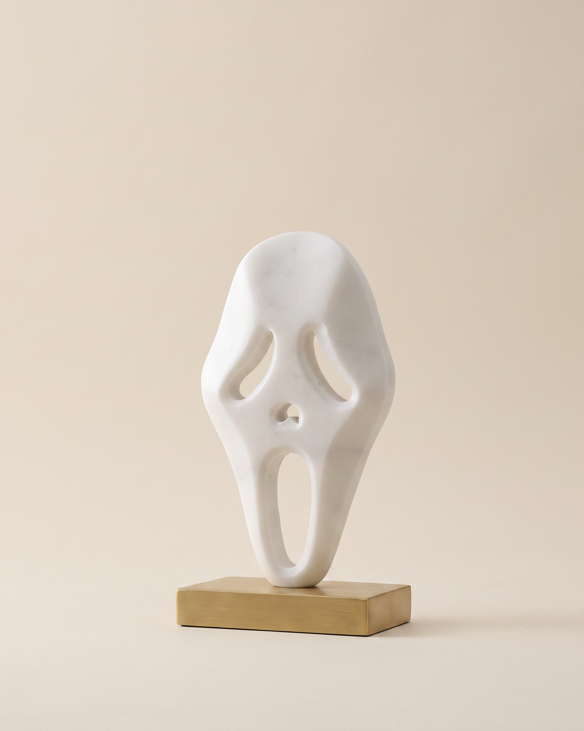 Ghost Decorative Object White - matte white ghost mask sculpture on brass plinth, ivory studio background