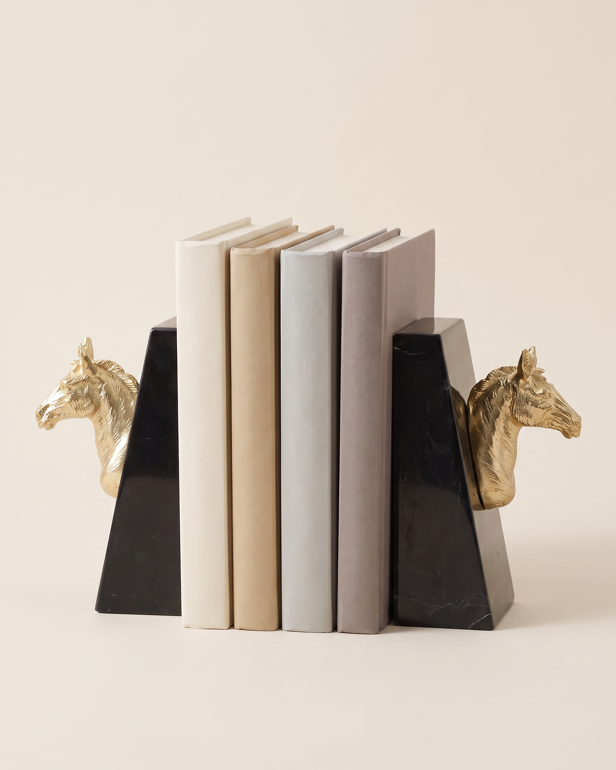 Gold Horse Head Bookends with Black Marble Base - studio view on ivory background, holding a row of plain books