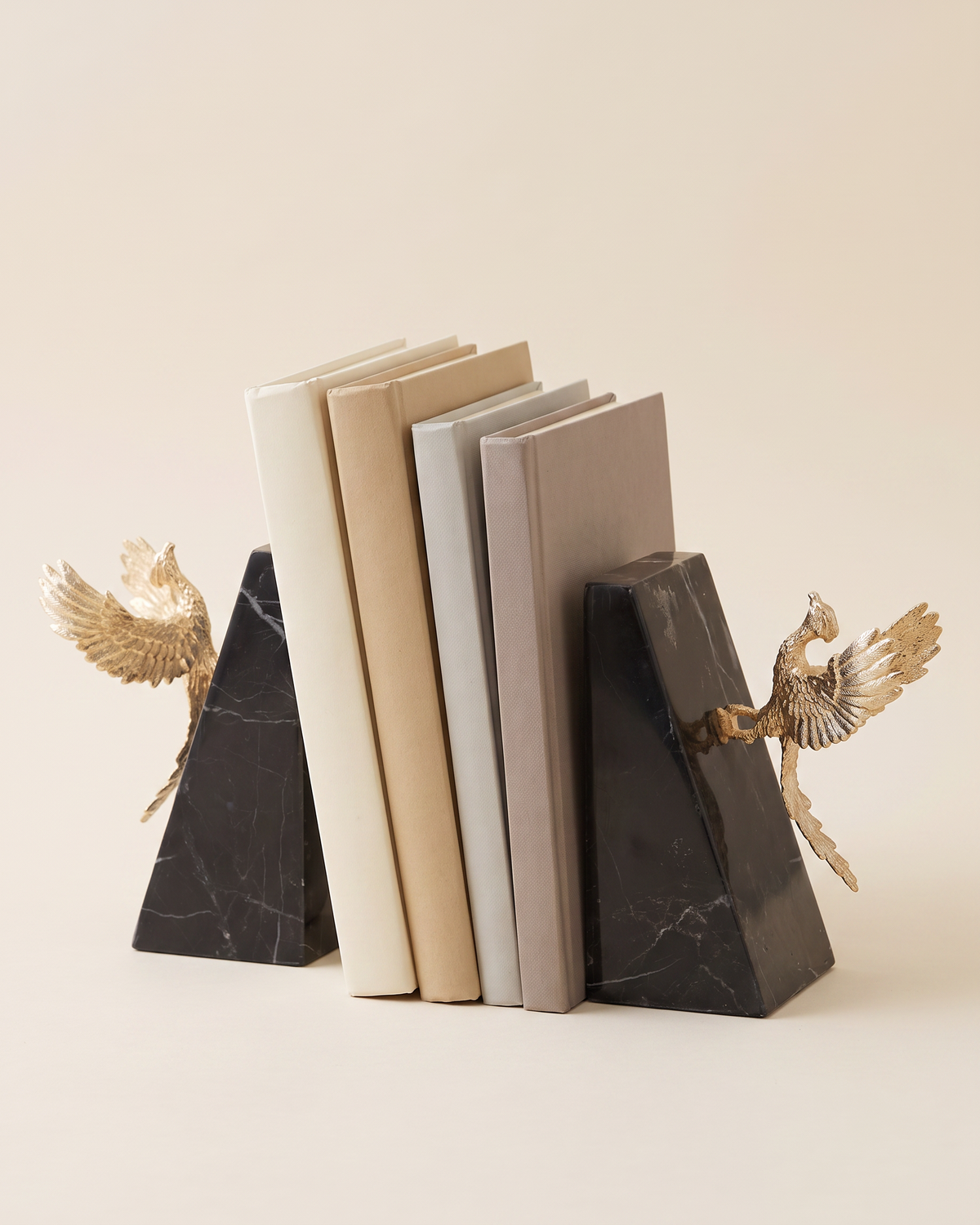 Gold Winged Bird Bookends with Black Marble Base - studio view on ivory background, holding a row of plain books
