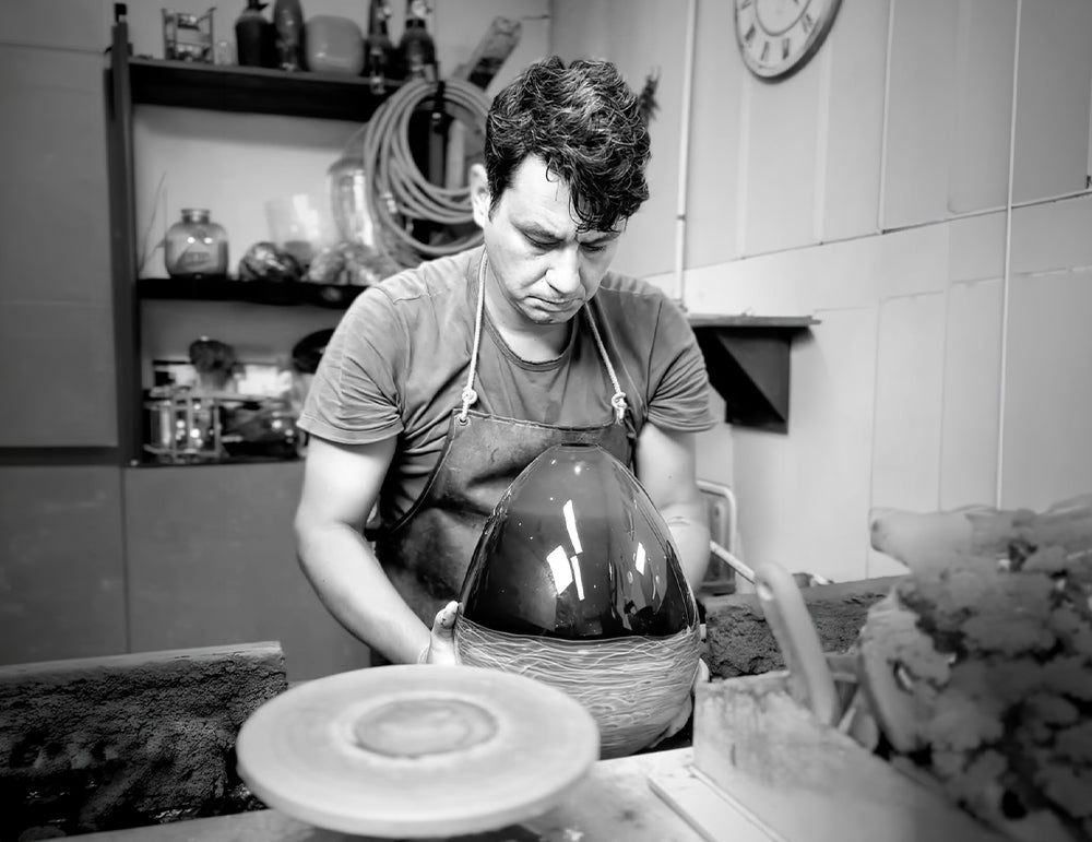 Agah Barış Can Aksakal shaping a hand-blown glass vessel in his studio