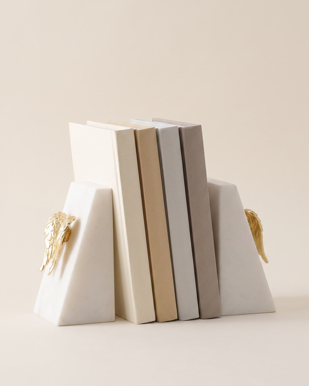 Angel Wing Bookends in White Marble - studio view on ivory background, holding a row of plain books