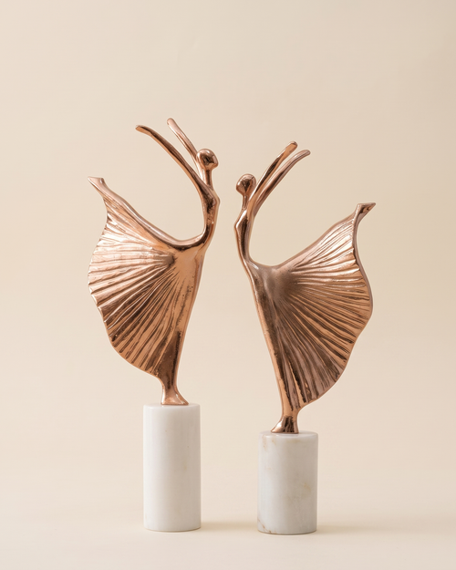 Ballerina Decorative Object IX - two copper dancer sculptures with pleated skirts on white marble bases, ivory studio background