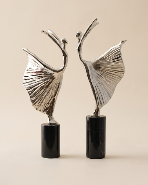 Ballerina Decorative Object XI - two silver dancer sculptures with pleated skirts on black marble bases, ivory studio background