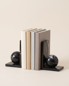 Black Marble Sphere Bookends - studio view on ivory background, holding a row of plain books