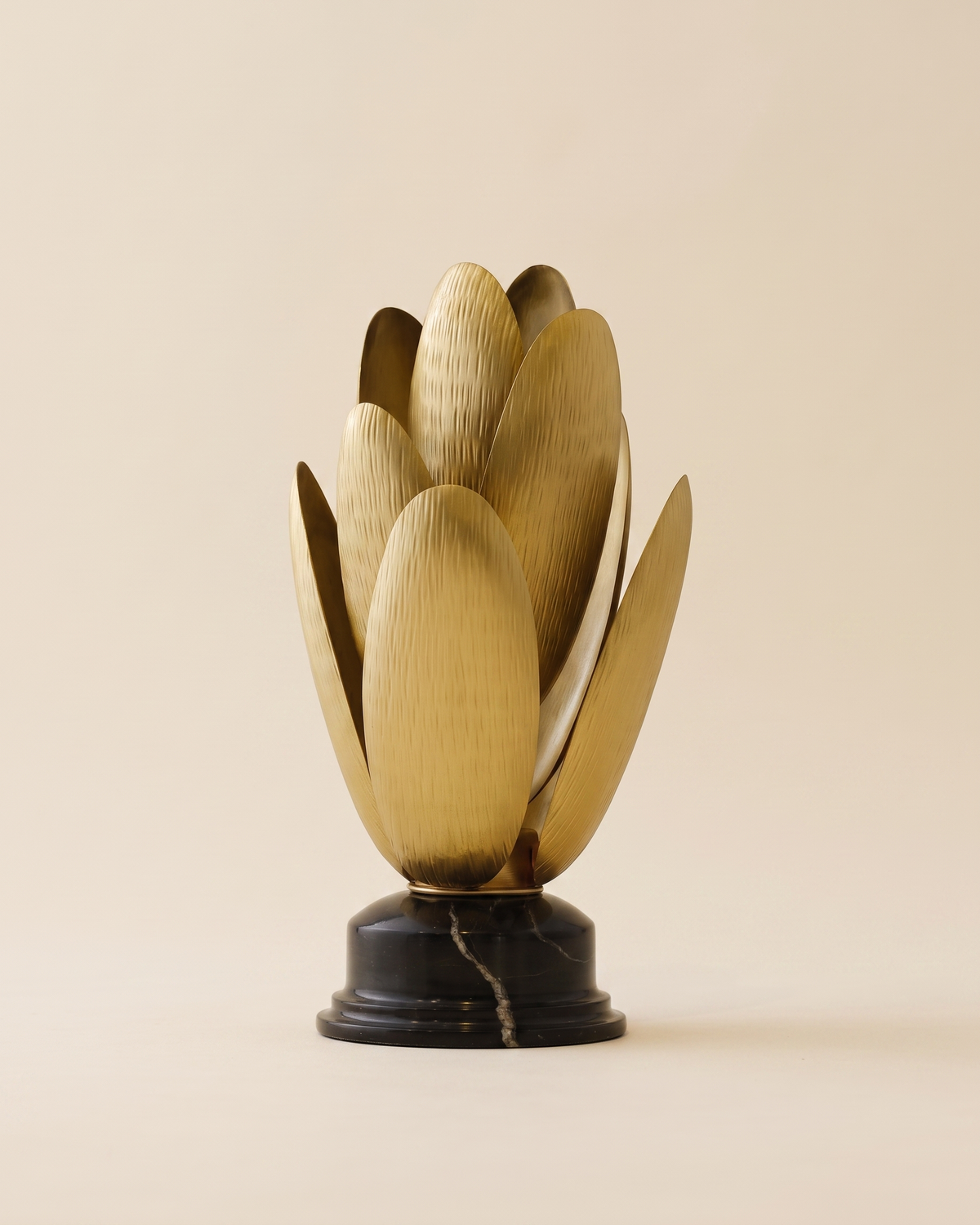 Brass Lotus Flame Sculptural Decor - layered brushed brass lotus bud on black marble pedestal, ivory studio background