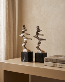 Brass Ribbon Sculpture on Black Marble — styled interior