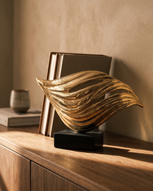 Brass wave sculpture on a walnut sideboard in afternoon light