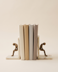 Thinking Man Bookend Set on Marble Base, Modern Literary Shelf Decor - studio view on ivory background, holding a row of plain books