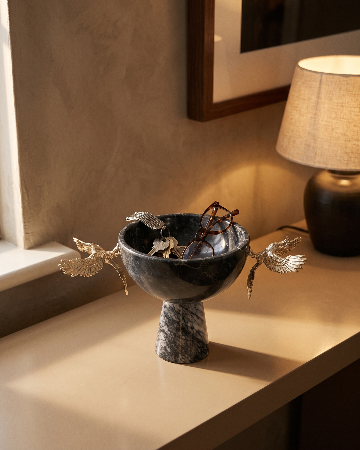 Marble footed bowl with gold phoenix figures on an entrance console, holding keys and glasses