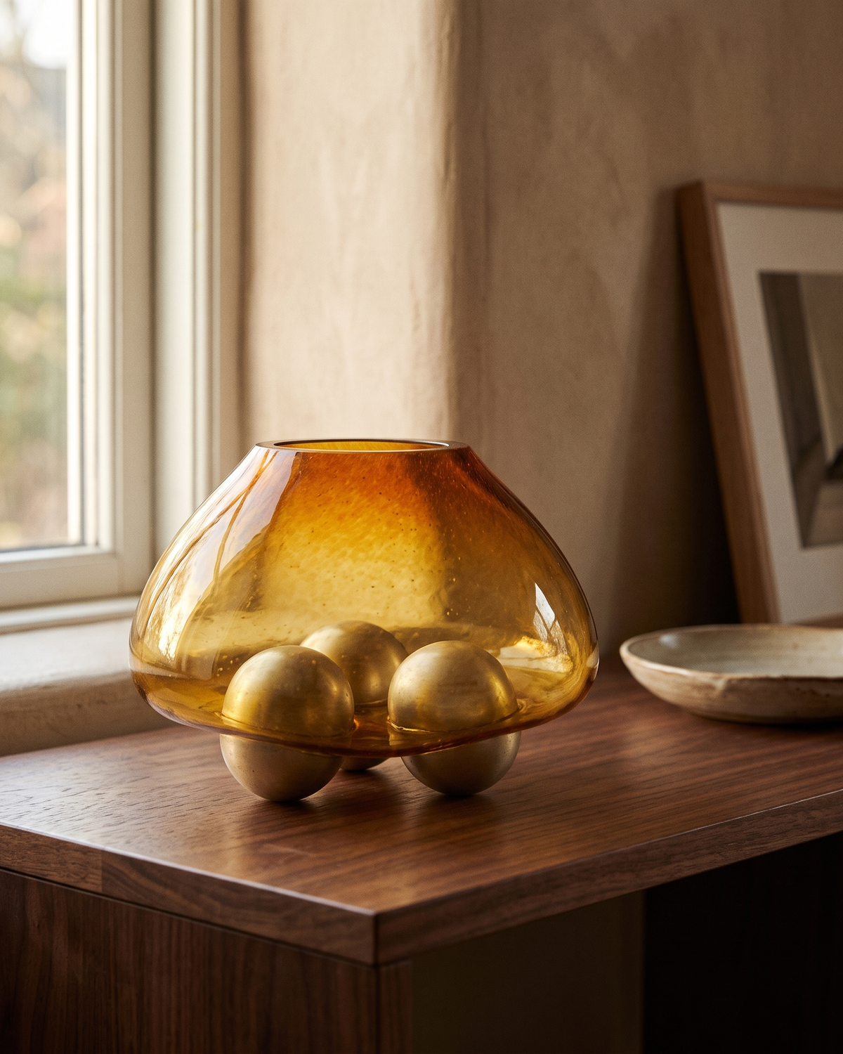 Glass Bowl with Three Brass Spheres styled in a warm interior setting