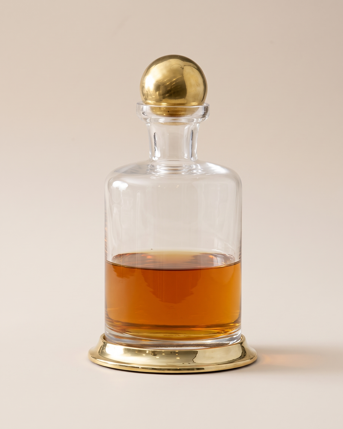 Glass Decanter with Brass Base & Sphere Lid (One Piece) on a warm ivory studio background