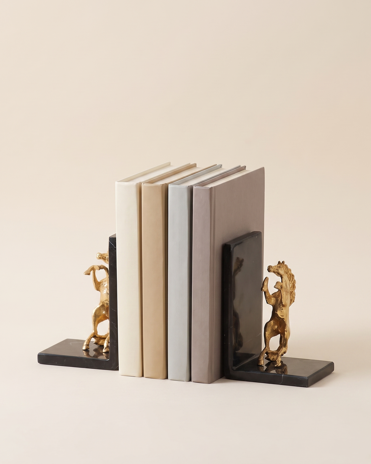 Golden Horse Bookends with Black Marble Base - studio view on ivory background, holding a row of plain books
