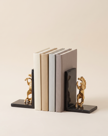 Golden Horse Bookends with Black Marble Base - studio view on ivory background, holding a row of plain books