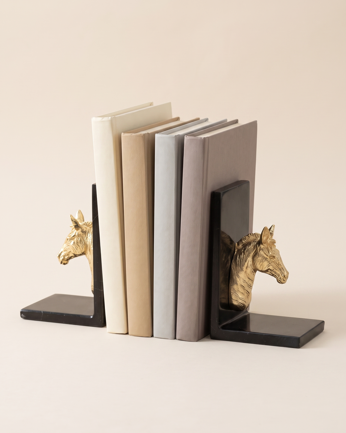 Golden Horse Head Bookends with Black Marble Base - studio view on ivory background, holding a row of plain books