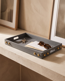 Grey leather tray with brass studs holding keys on an entrance console
