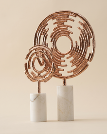 Icon Decorative Object II - two pierced copper disc sculptures on white marble bases, ivory studio background