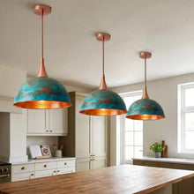 Three pendant lights hanging above a kitchen island with white cabinets and a window in the background.