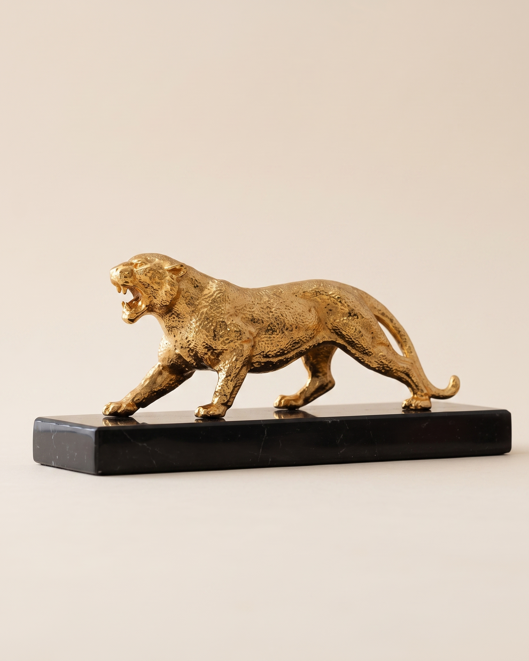 Jaguar Decorative Object II - gold brass prowling panther sculpture on black marble slab, ivory studio background