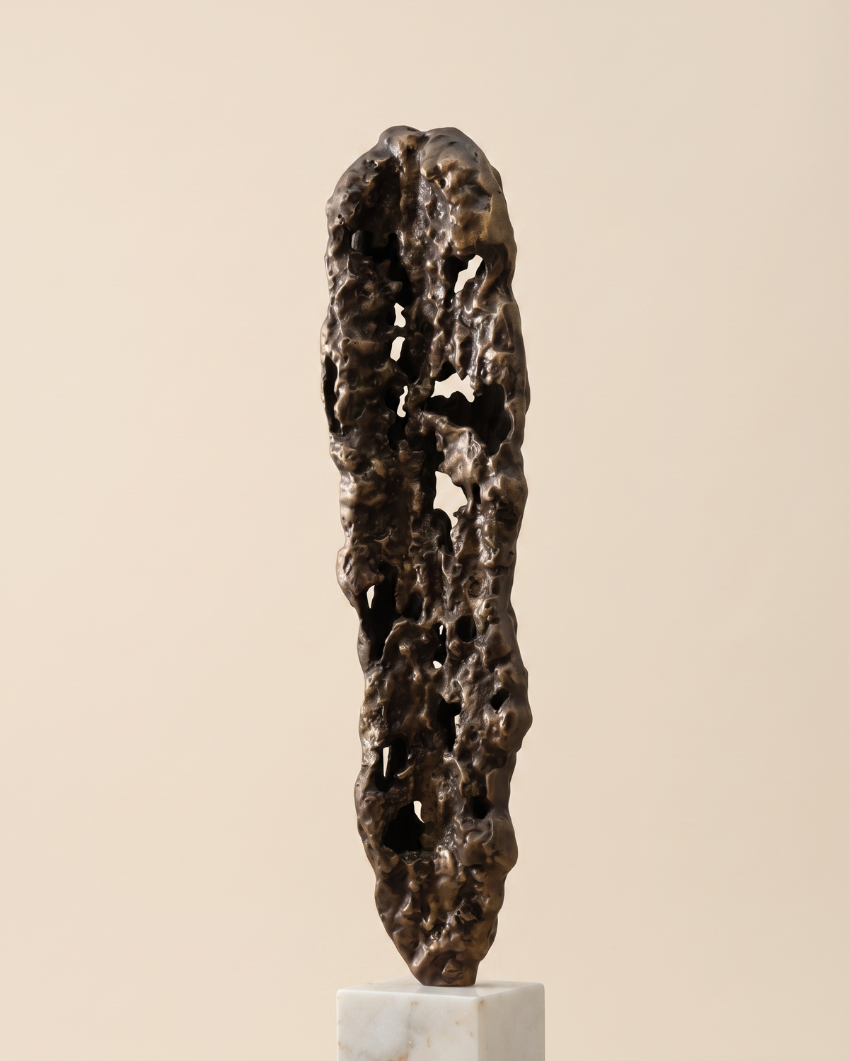 Lead Decorative Object II - tall eroded bronze pod sculpture on white marble cube, ivory studio background