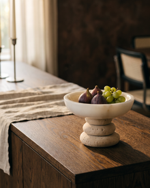 White marble bowl on a travertine base holding figs on a dining sideboard