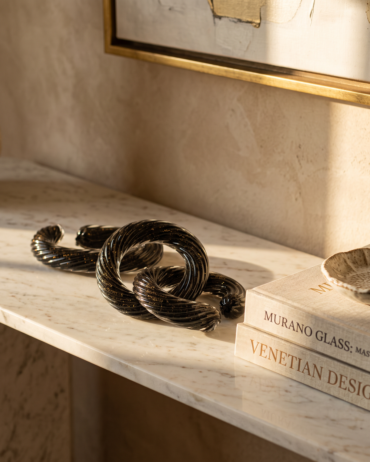 Murano glass chain laid along a marble console with art books