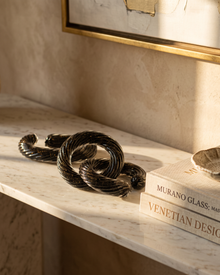 Murano glass chain laid along a marble console with art books