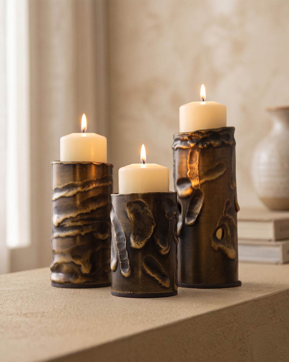 Molten Brass Candle Holder Textured Aged Brass - with lit candles, styled on a warm beige console in a cosy interior