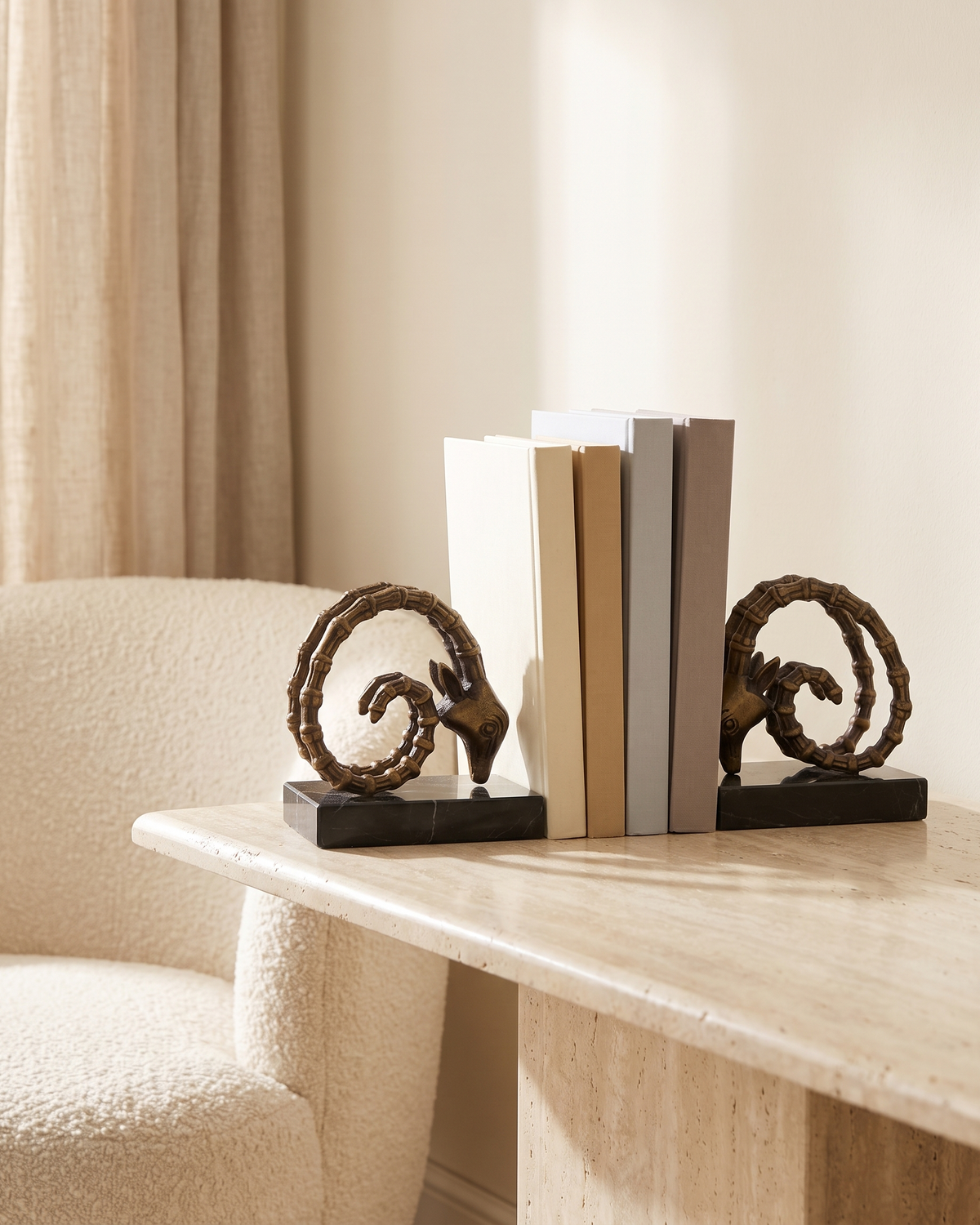Ram Horn Bronze Bookends with Black Marble Base - styled on a travertine console holding plain books