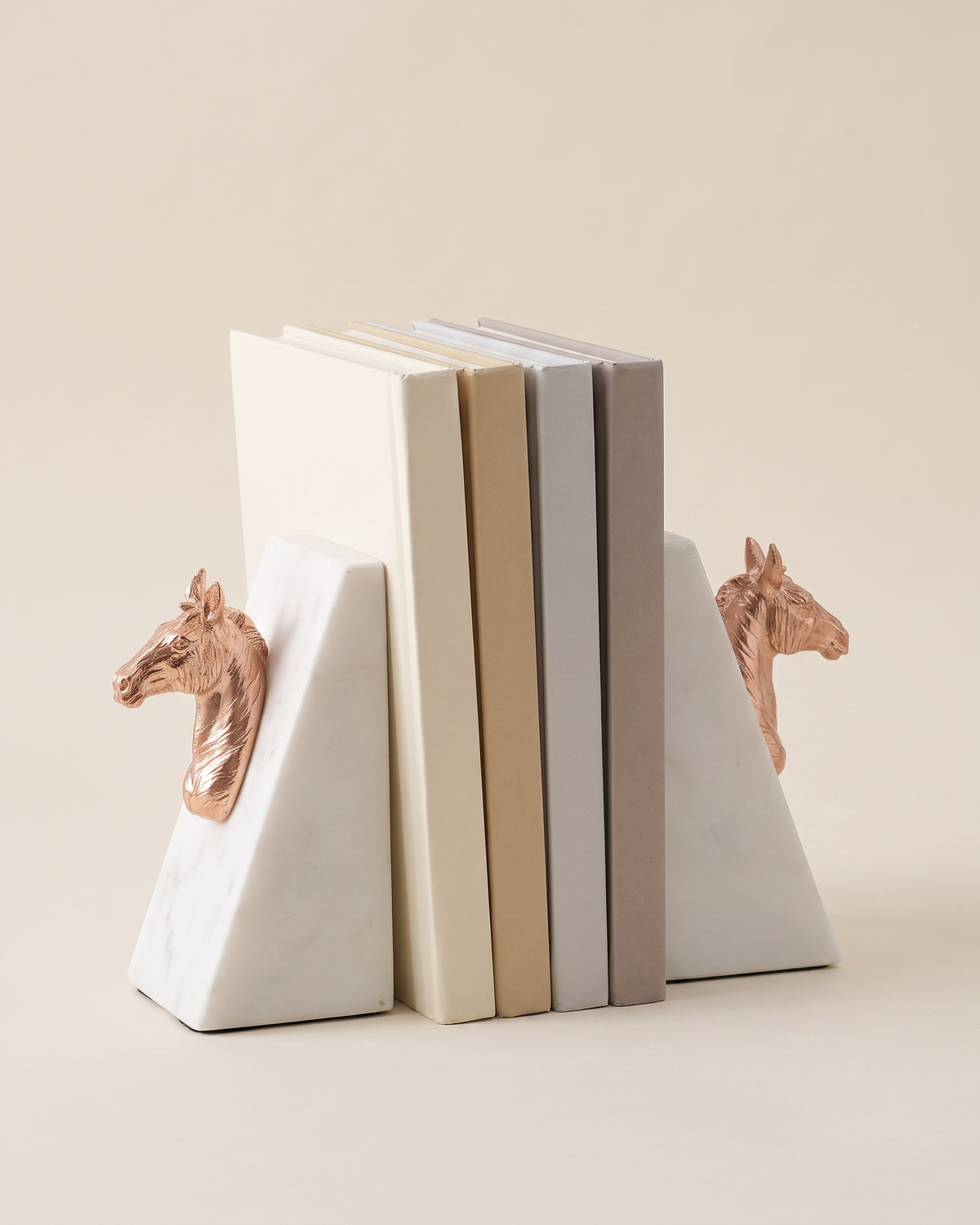 Rose Gold Horse Head Bookends with White Marble Base - studio view on ivory background, holding a row of plain books