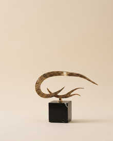 Side Flame Decorative Object - horizontal striated gold brass flame on black marble cube, ivory studio background
