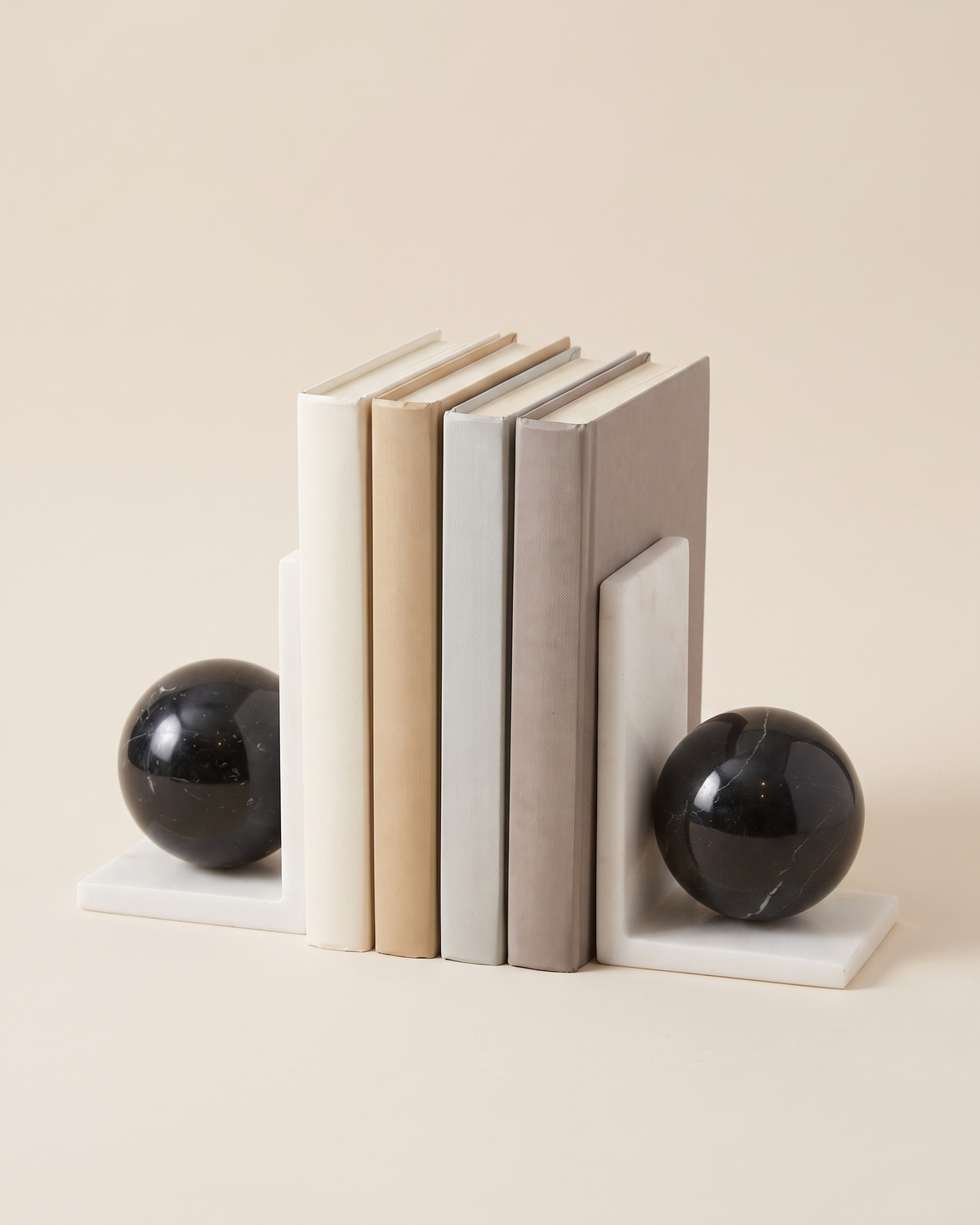 White Marble & Black Sphere Bookends - studio view on ivory background, holding a row of plain books