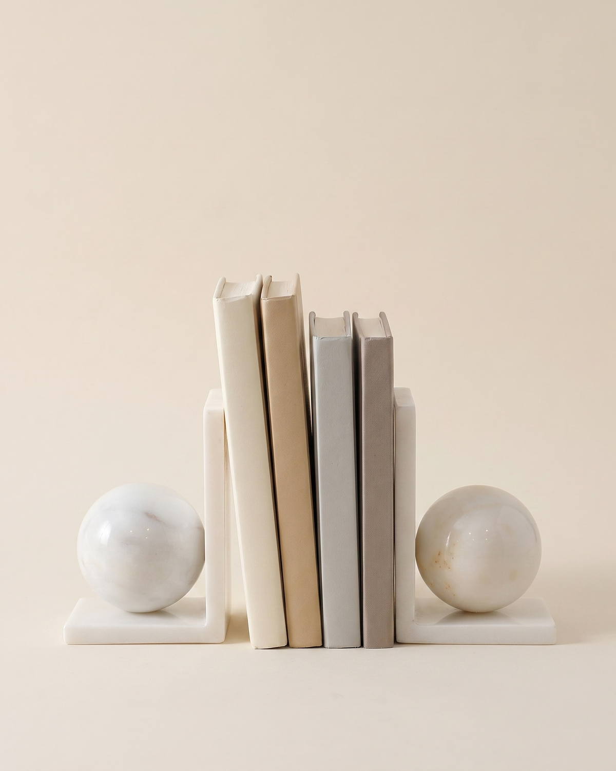 White Marble Sphere Bookends - studio view on ivory background, holding a row of plain books